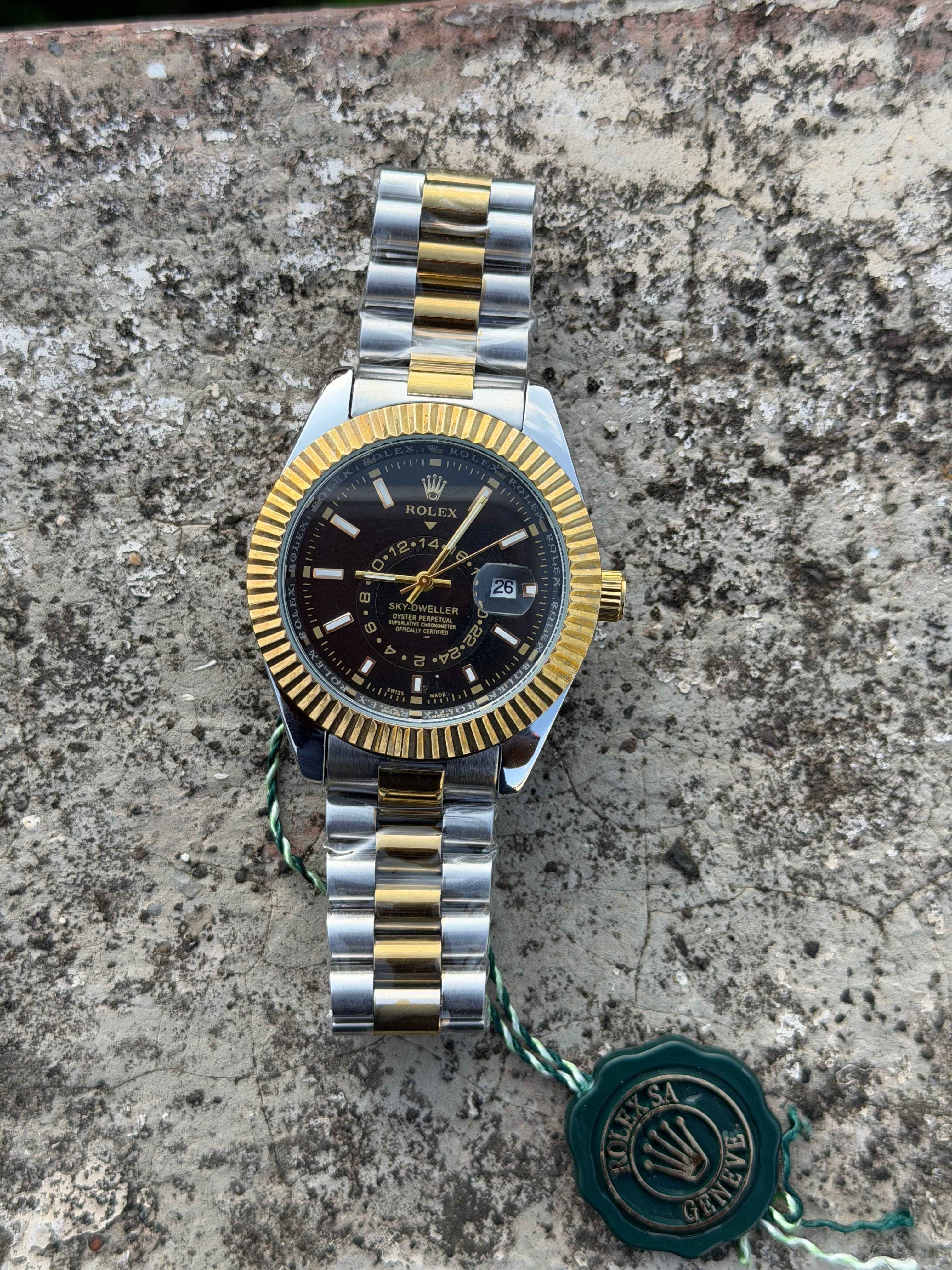 Rolex Sky-Dweller watch featuring a black dial and a two-tone gold and steel bracelet.